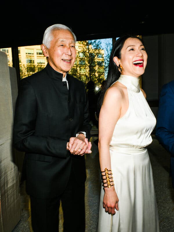 Oscar Tang, in a black suit, stands with Agnes Hsu-Tang, in a long white silk dress.