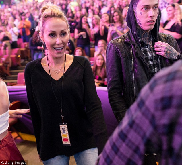 That's my girl: Tish Cyrus is accompanied by heavily tattooed son Trace (R) as she takes in her daughter's latest show