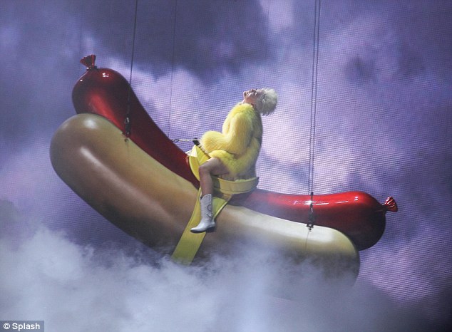 Any chance of fries with that? Miley swings from a large hot dog, as you do, during the Bangerz show on Thursday