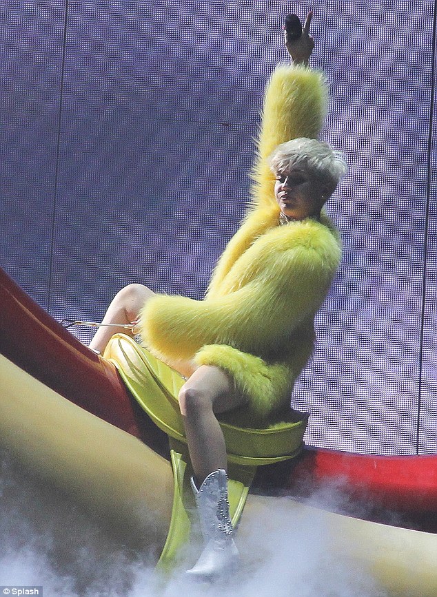 Balancing act: Miley holds on as she is swung above the stage