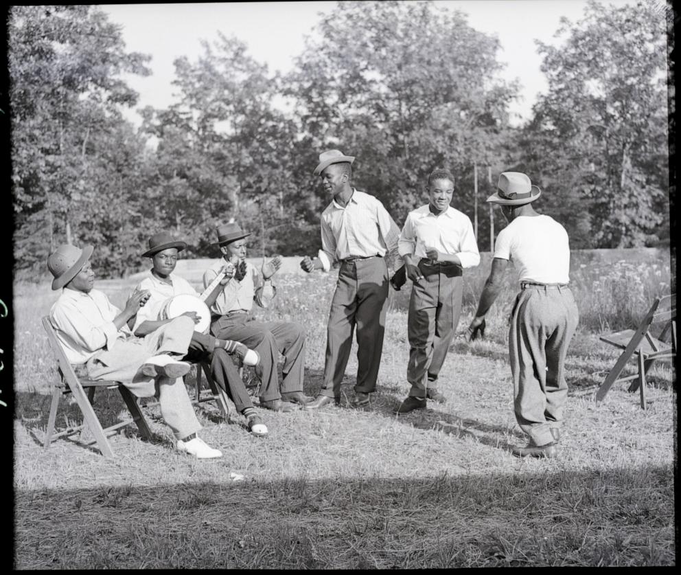 In this undated file photo, a group of African American men are seen singing and dancing on grass.