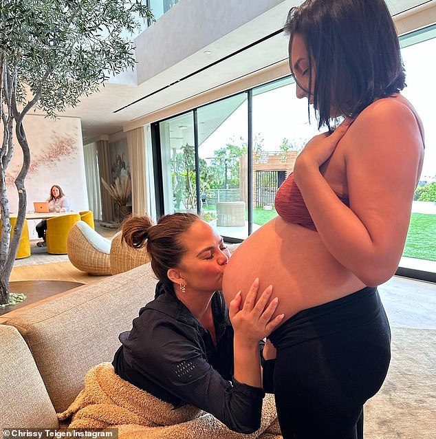 Sharing a moment: Teigen shared this snap of her kissing her surrogate Alexandra's bump