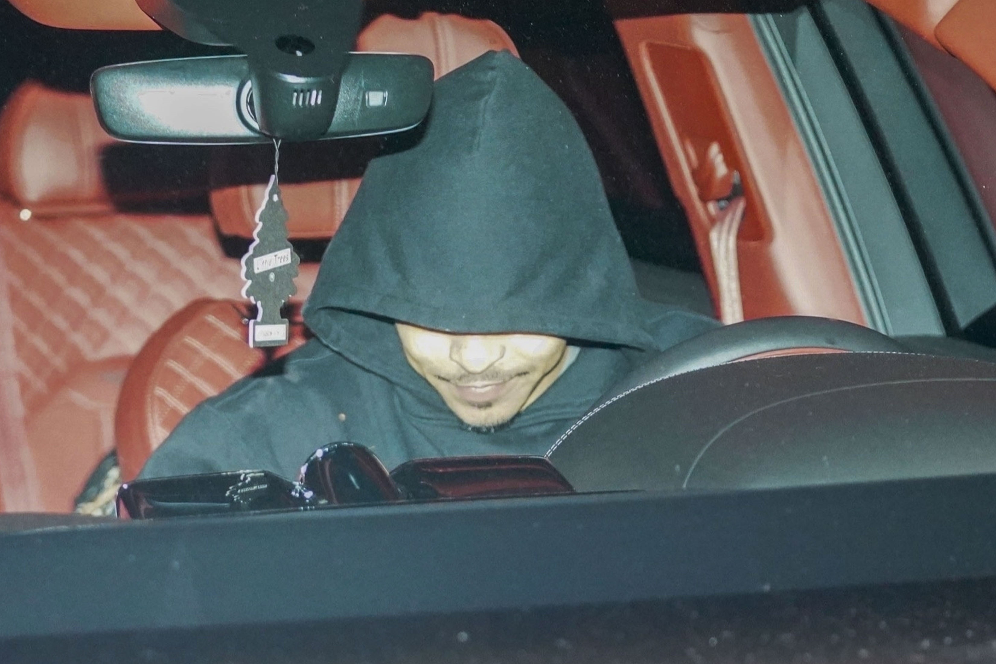 a hooded person driving a car