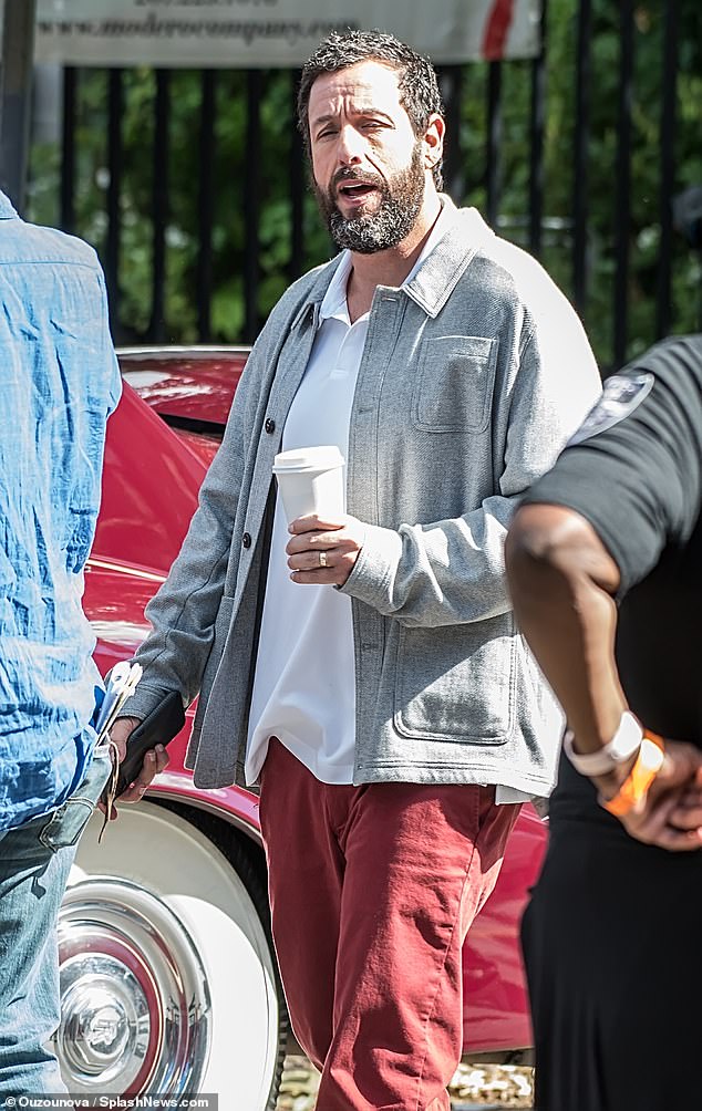 Casual look: Sandler was spotted wearing a white polo shirt over a thicker grey button-down down shirt as he walked through the set with a coffee and his phone