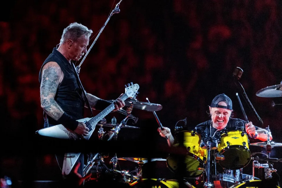 A heavy-metal guitarist and drummer perform onstage