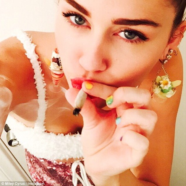 The big smoke: Sure to conjure up controversy, Miley, was pictured smoking a suspicious looking cigarette while modelling sundae earrings, writing: 'put n werk'