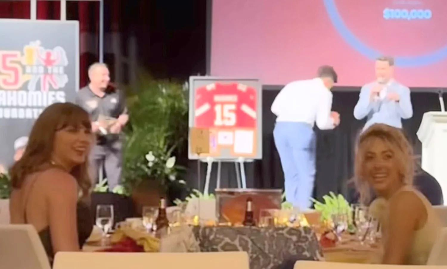 Taylor Swift sways a towel in her hand as she watches boyfriend Travis Kelce catch passes from Patrick Mahomes inside charity auction in Las Vegas. During the gala she was joined at her table with Brittany Mahomes and Patrick who leaned over their chairs to watch Travis warm up the crowd to help bid big money for pairs of her upcoming tour tickets as the crowd went wild inside the exclusive auction in the Bellagio hotel.