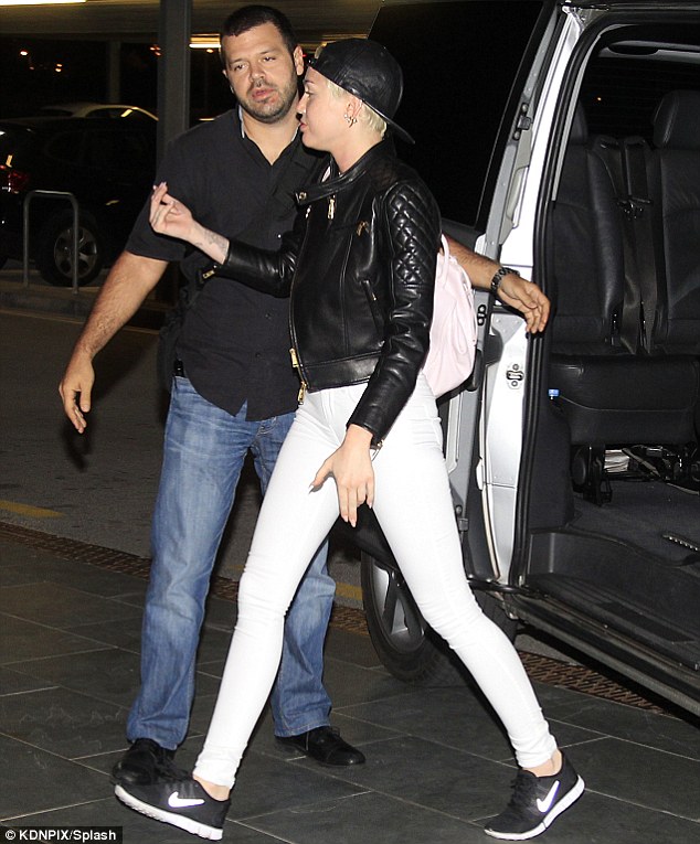 Tomboy chic: Miley highlighted her long slender legs in skintight white trousers, with a leather jacket and a backwards baseball cap