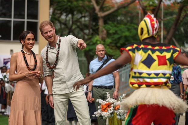 Britain's Prince Harry (2nd L), Duke of Sussex, and Britain's Meghan (L), Duchess of Sussex, look at people dancing as they arrive at the Lightway Academy in Abuja on May 10, 2024 as they visit Nigeria as part of celebrations of Invictus Games anniversary. (Photo by Kola SULAIMON / AFP) (Photo by KOLA SULAIMON/AFP via Getty Images)