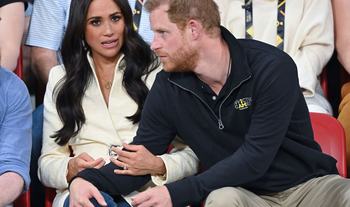 prince harry leans over sitting meghan markle