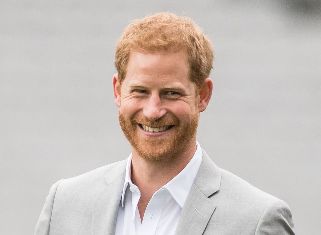 Prince Harry smiling in grey suit 