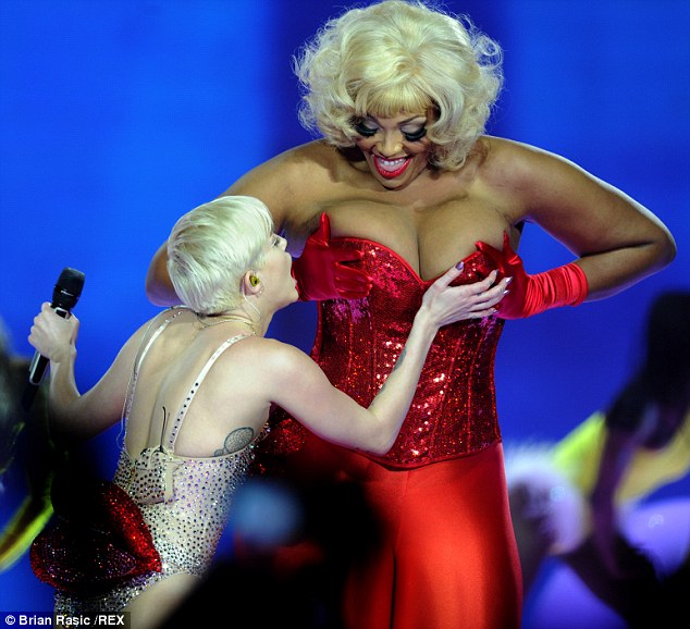 Up close: She was seen getting to grips with a busty backing dancer, who was dressed in a sparkly red corset