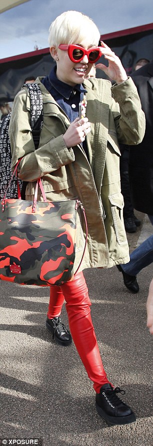 Coordinated: Miley matched her red and camouflage bag to her green khaki jacket, red sunglasses and leather trousers