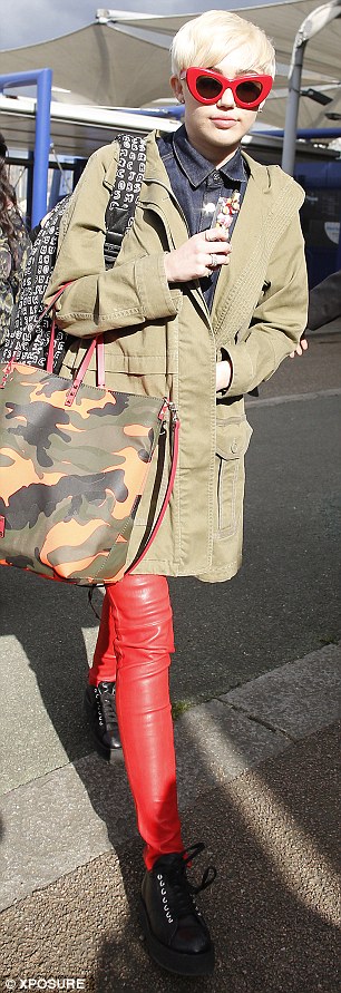 Coordinated: Miley matched her red and camouflage bag to her green khaki jacket, red sunglasses and leather trousers