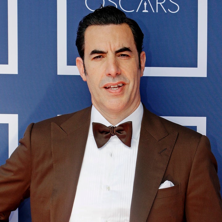 Man in brown jacket and white pants posing at the Oscars