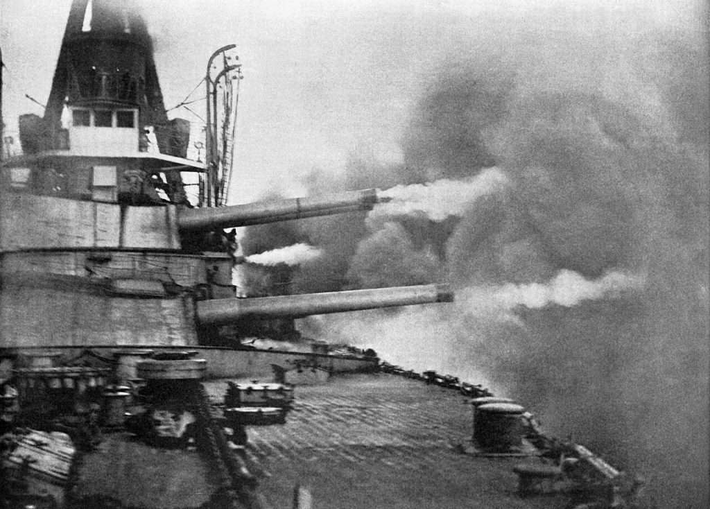 Ten of her 12-inch guns firing a boadside trained to port during gun trials. 