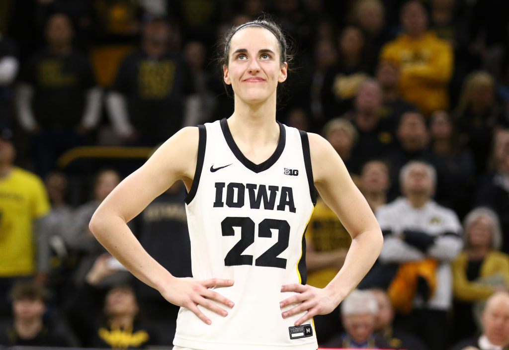 Caitlin Clark looks on during a game with her hands on her hips.