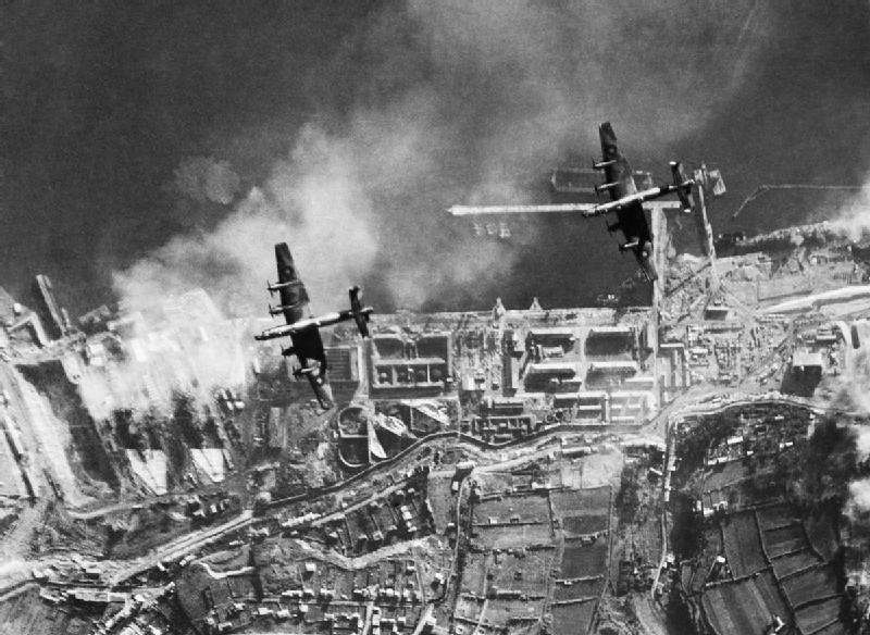 Two Handley Page Halifaxes fly towards the drydock where the Gneisenau and Scharnhorst are berthed during a daylight raid. 