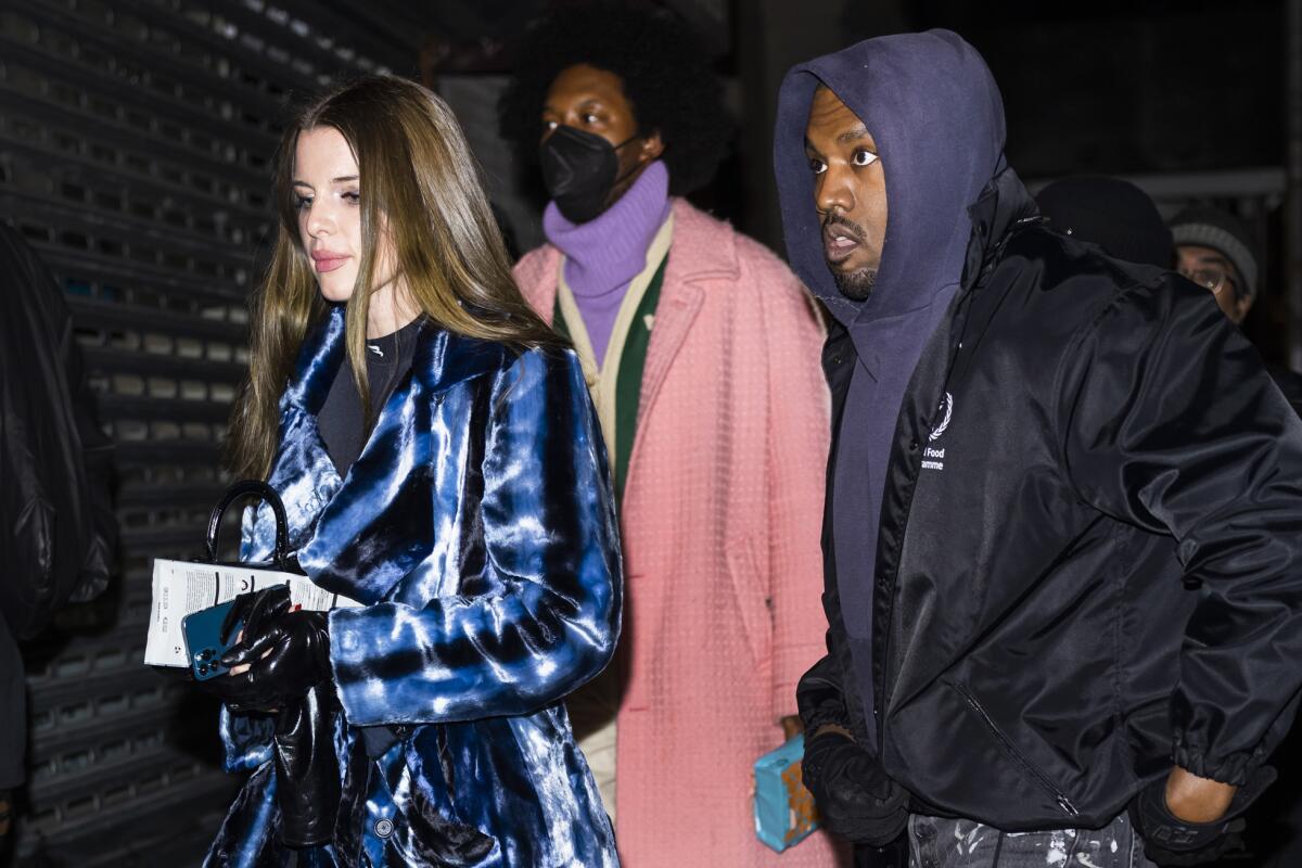 Julia Fox and Ye walk with a man behind them.