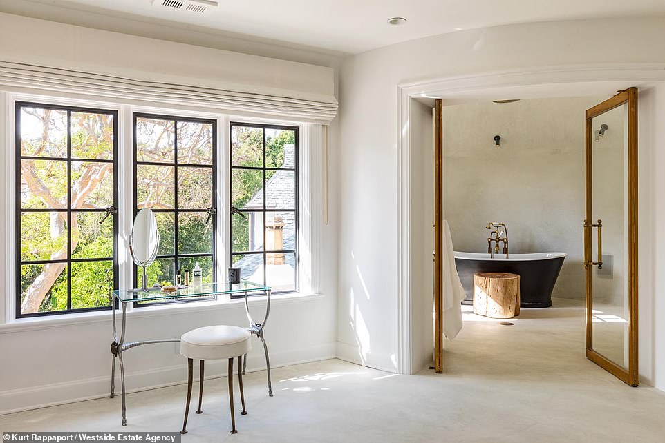 Lovely: The ensuite bathroom includes a sitting area and stand alone clawfoot bathtub positioned behind large glass doors