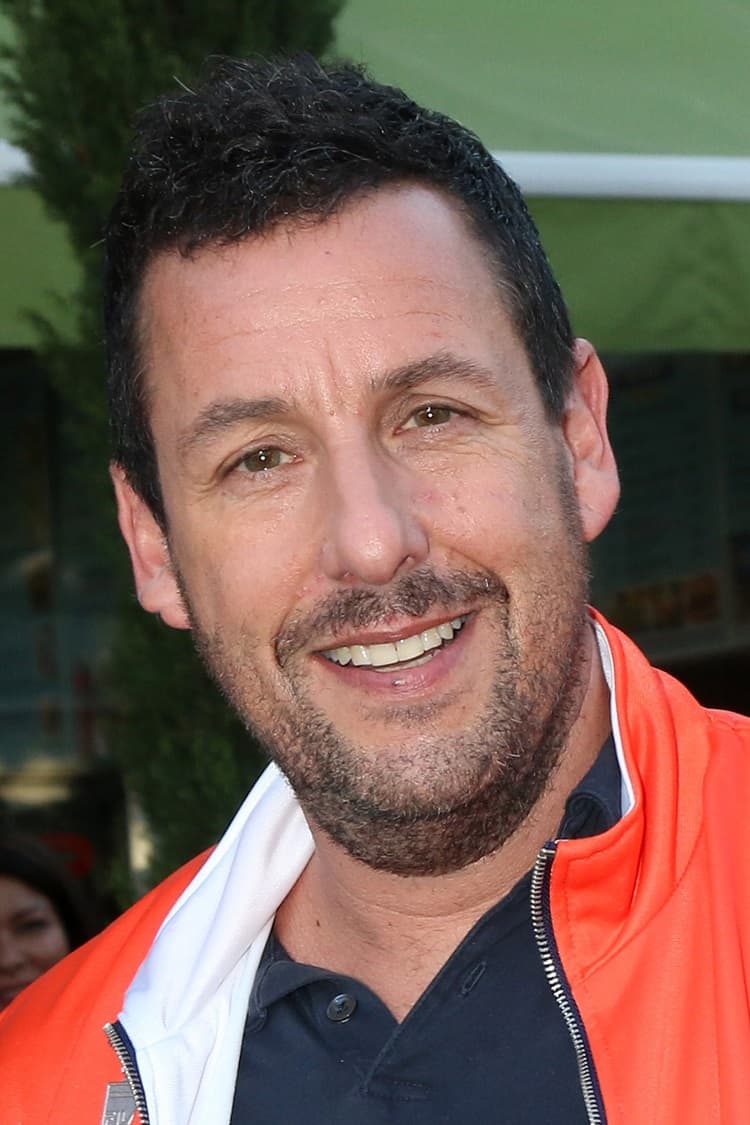 close-up photo of actor Adam Sandler sporting an orange sports jacket and a stubble