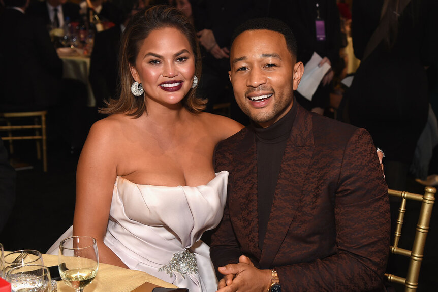 John Legend and Chrissy Teigen seated at an award show