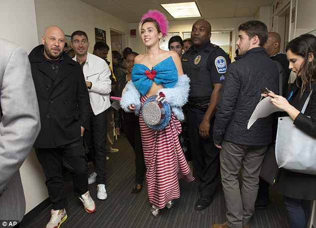 Unusual outfit: Miley Cyrus, wearing a patriotic bow and a skirt, walks through a dorm at George Mason University Saturday