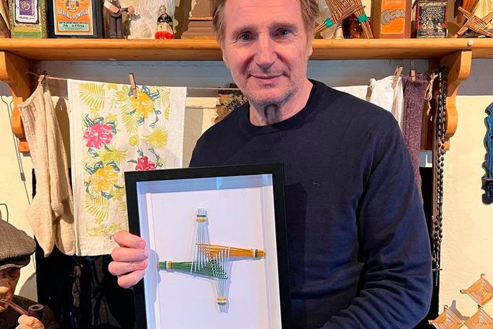 Liam Neeson holding a St Brigid's cross presented to him by the villagers