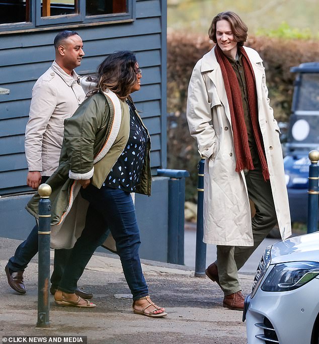 Alison bundled up in a khaki coat and blue jeans, teamed with gold sandals and orange tinted sunglasses