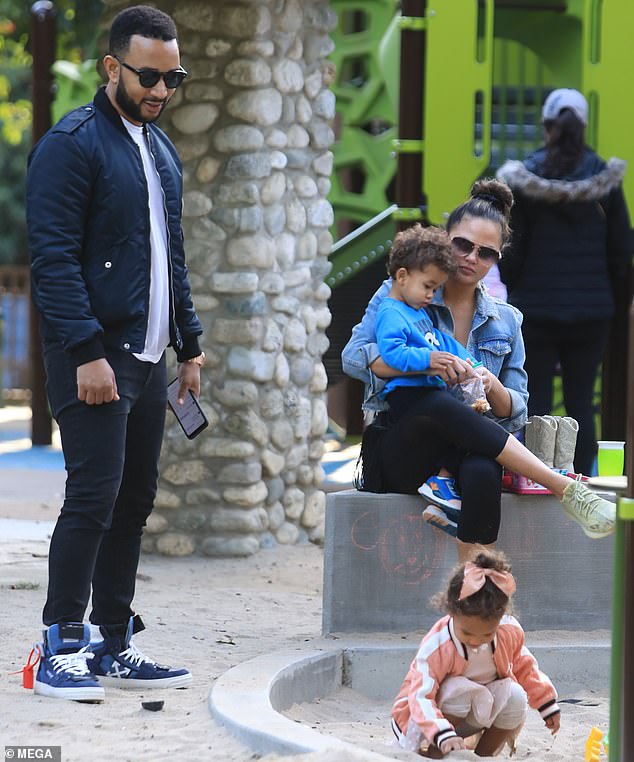 Keeping him close: Chrissy held her youngest in her lap as Luna played in the sand