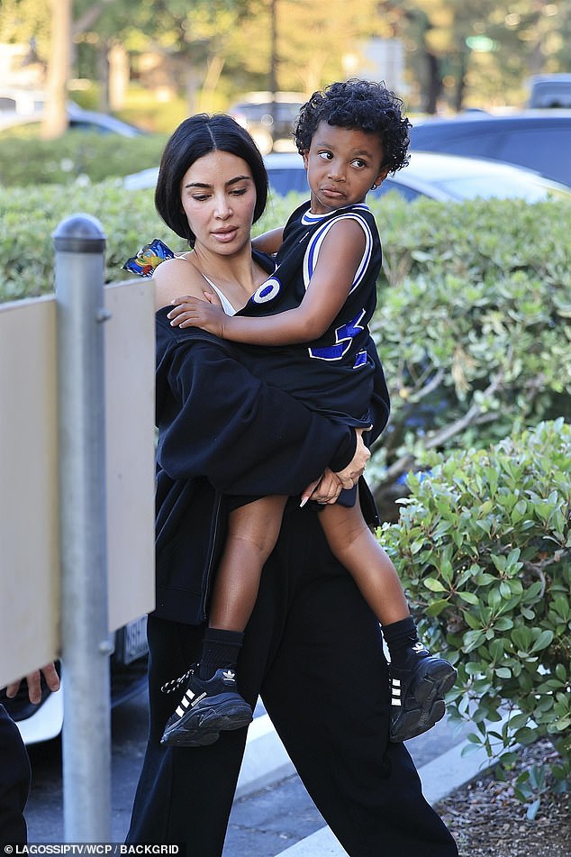 She carried her youngest son Psalm, five, in her arms as she made her way to the gymnasium's entrance