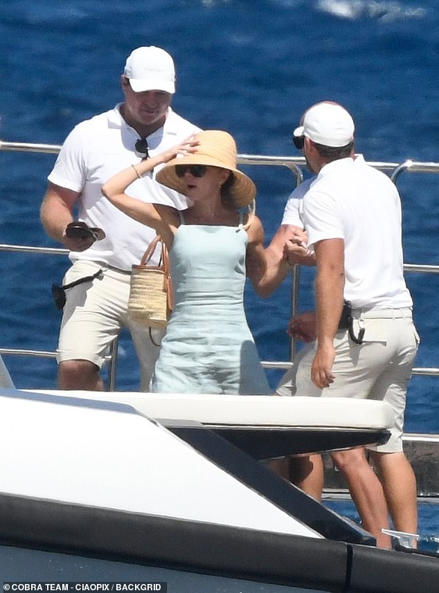 Posh was helped up by a trio of crew members, looking incredibly chic in her boat look